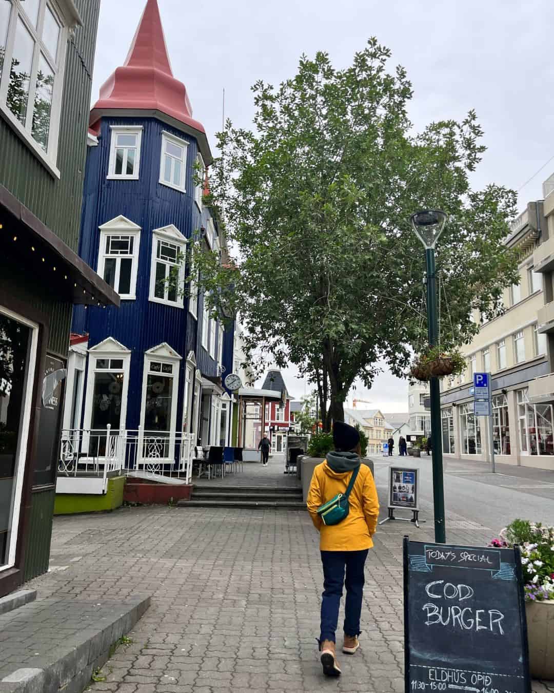 A woman walking around a town in Iceland wearing the Coalatree Trailhead pants and other warm outdoor attire.