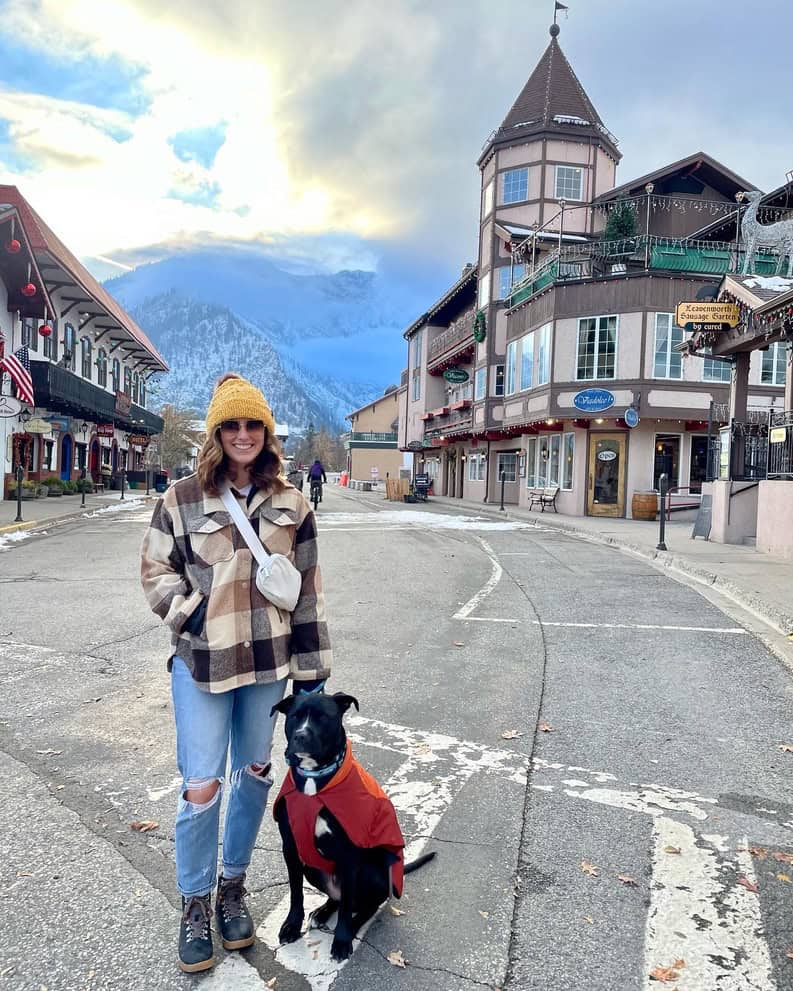 A woman in the late fall visiting Leavenworth, Washington with her dog while wearing a flannel, jeans, beanie, and hiking boots. This is the perfect example of what to wear in the fall in Seattle.