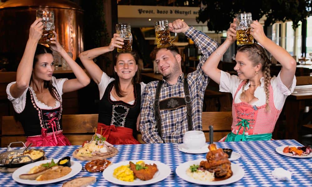 Four friends at Oktoberfest in Leavenworth at a bar with beer and german food.