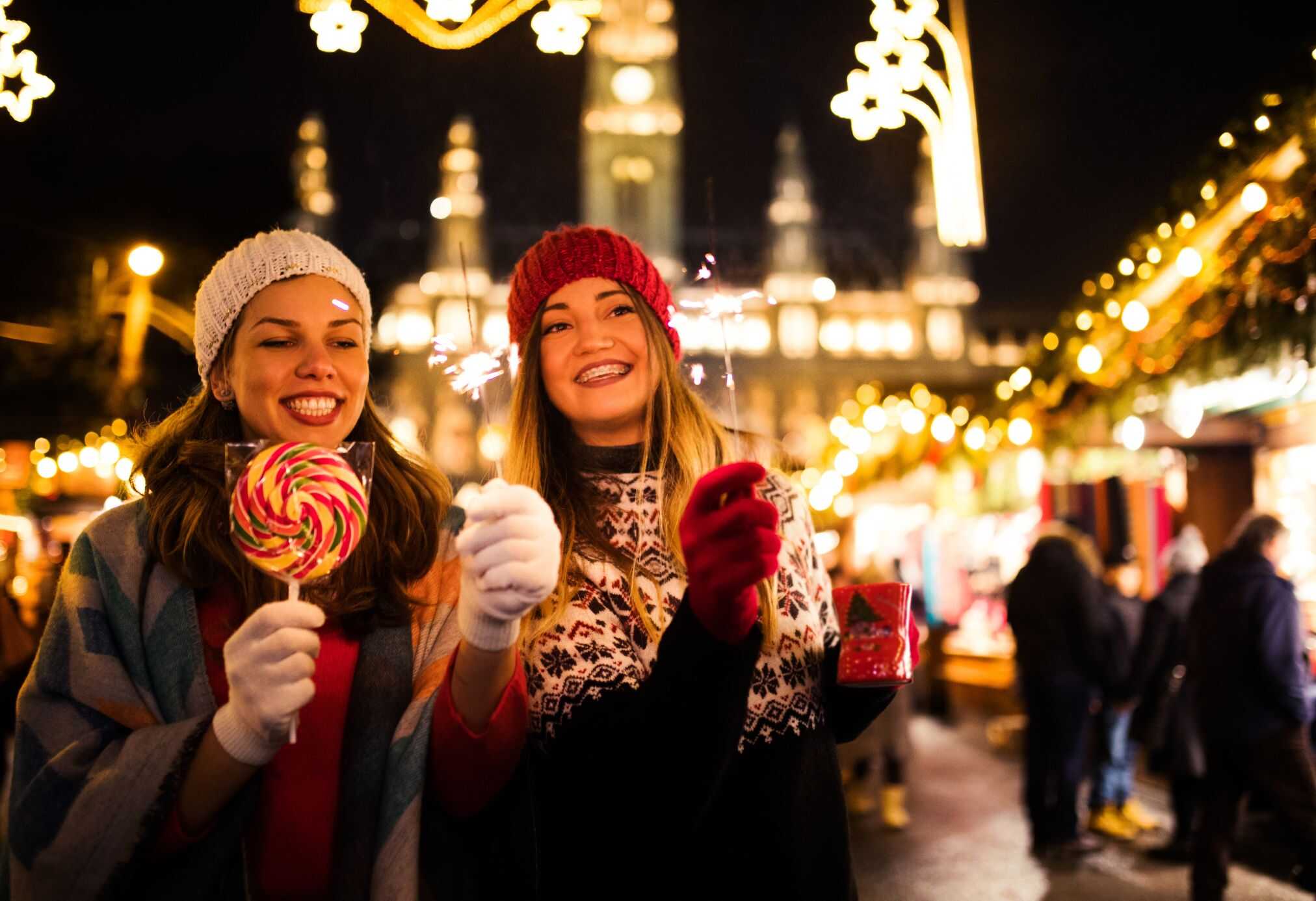 Two friends spending time in Switzerland on their winter itinerary. This has one of the beautiful holiday markets in the background in December.