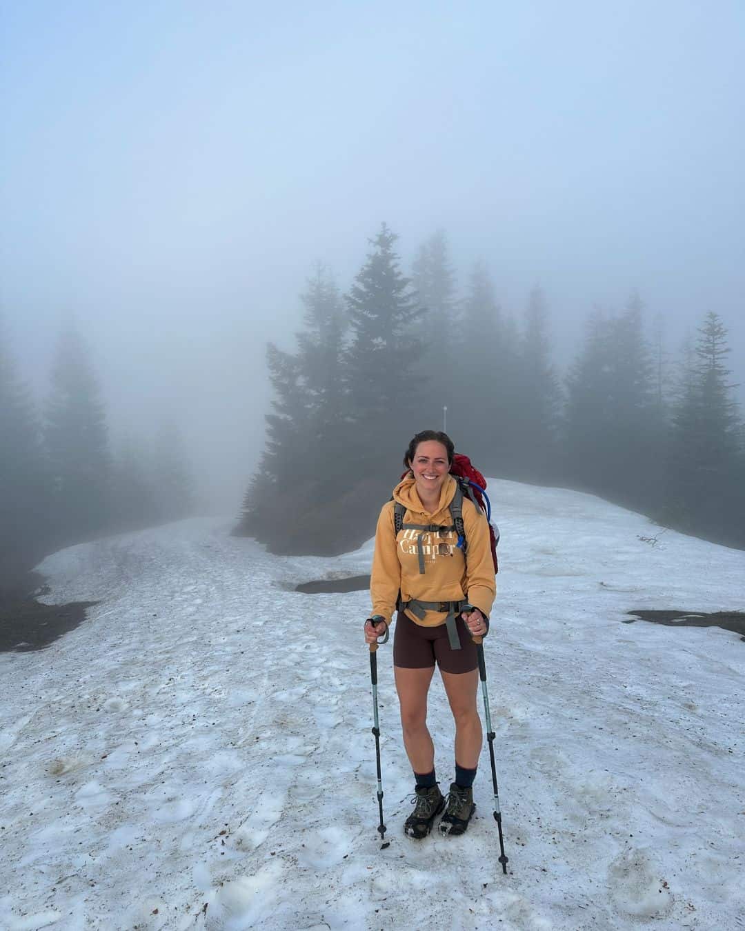 A woman hiking in the snow during a foggy day.